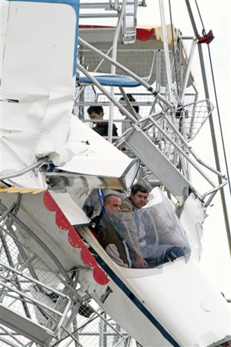 Two men and their ultra-light plane hang from a Ferris wheel while two children sit in a carriage near the top of the ride at a country festival at Old Bar, Australia, Saturday, Oct. 1, 2011. The four people were trapped in the tangled wreckage for hours after the plane crashed into the ride. 